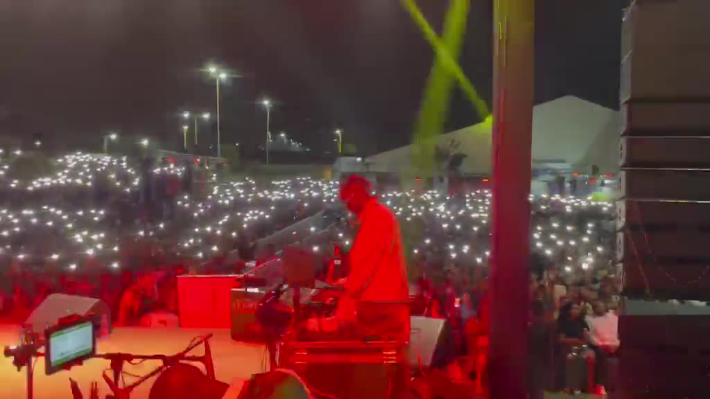 Scène baignée de rouge face à une foule qui brandit ses téléphones