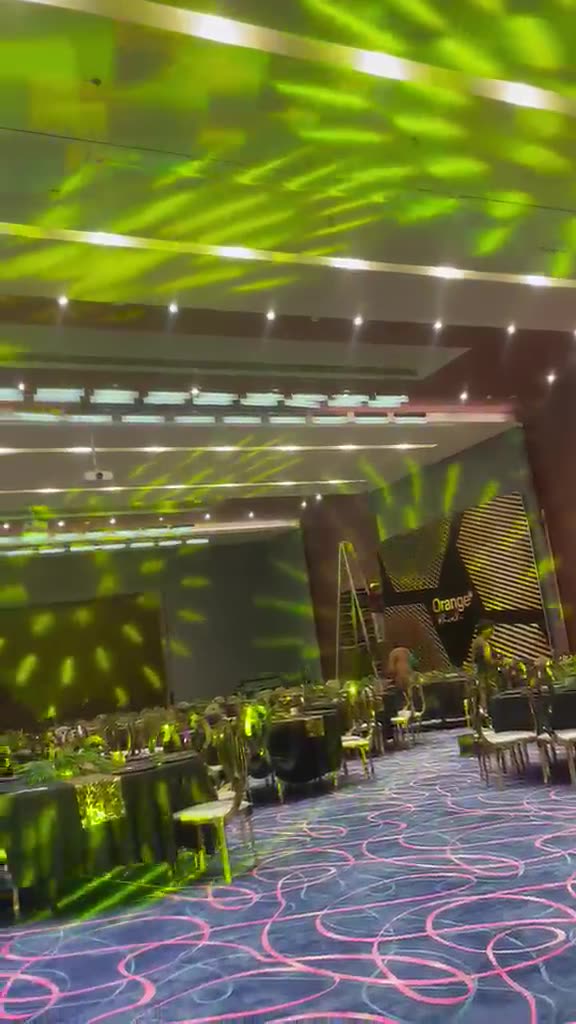 Salle de gala avec gobos verts projetés au plafond et tables dressées